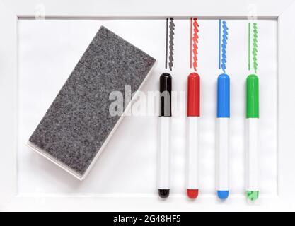 Colored markers and erasing sponge on a white board. Stock Photo