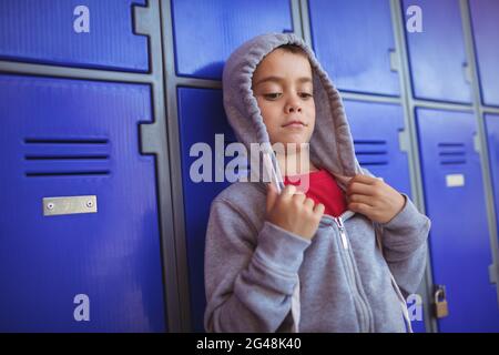 Boy wearing hooded shirt by lockers Stock Photo