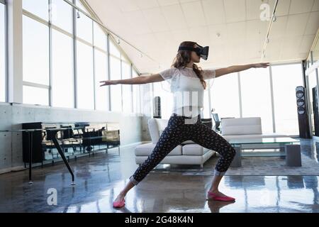 Businesswoman wearing virtual reality simulator exercising in office Stock Photo