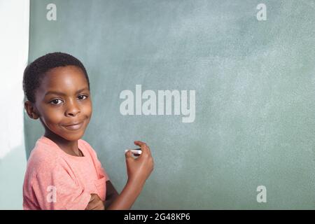 Portrait of boy standing by greenboard Stock Photo