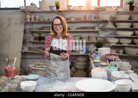 Portrait of female potter using digital tablet Stock Photo