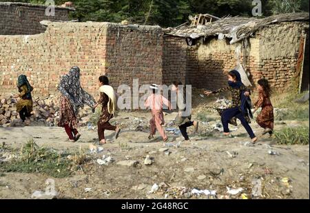 Peshawar, Pakistan. 19th June, 2021. Afghan refugee children play on the eve of the World Refugee Day on the outskirts of Peshawar, Pakistan, on June 19, 2021. Pakistan currently hosts more than 1.4 million registered Afghan refugees who have been forced to flee their homes, according to the United Nations High Commissioner for Refugees (UNHCR). Credit: Saeed Ahmad/Xinhua/Alamy Live News Stock Photo