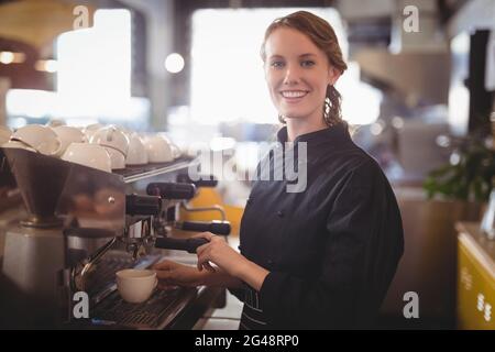 Portrait of smiling young waitress using espresso maker Stock Photo