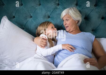 Grandmother and granddaughter interacting with each other on bed Stock Photo