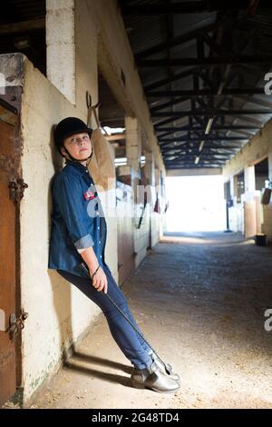 Girl leaning on wall in the stable Stock Photo