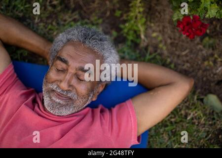 Senior male resting with closed eyes on exercise mat Stock Photo