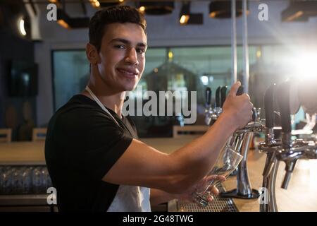Portrait of bartender pouring beer from tap Stock Photo