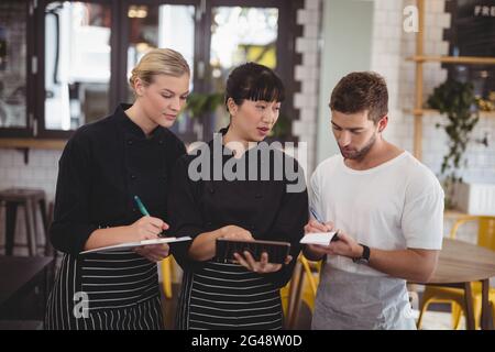Young waiter and waitress discussing over digital tablet Stock Photo