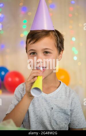 Boy blowing a party horn during birthday party Stock Photo