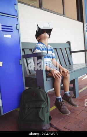Boy using virtual reality glasses while sitting on bench Stock Photo