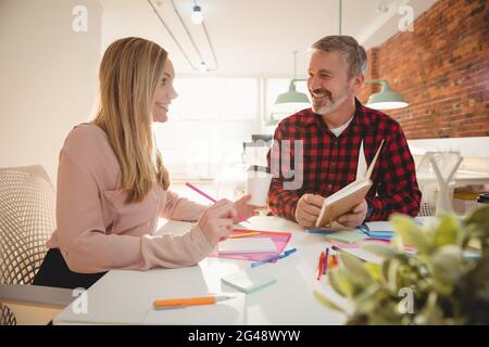Smiling executives discussing over diary Stock Photo