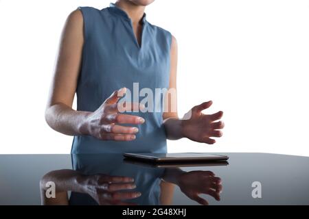 Mid section of businesswoman gesturing over digital tablet at table Stock Photo