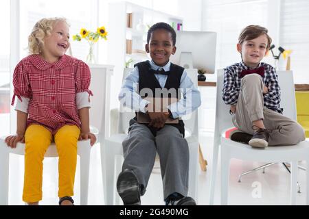 Portrait of male colleagues sitting with businessman on chairs at office Stock Photo
