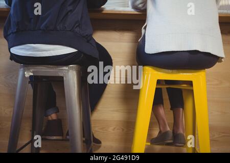 Low section of couple sitting on stools Stock Photo