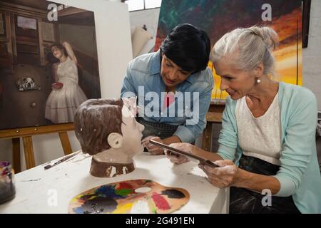 Woman using digital tablet while painting a sculptor Stock Photo