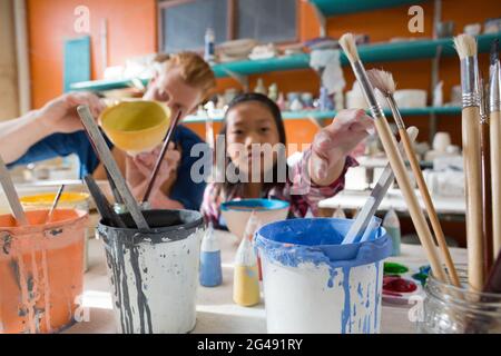 Male potter and girl painting bowl in pottery workshop Stock Photo - Alamy