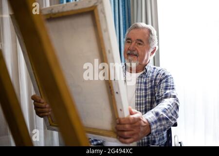 Senior man looking at painting while sitting on wheelchair Stock Photo