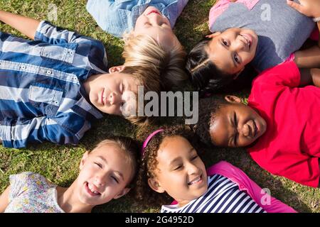Overhead view of children lying on field Stock Photo