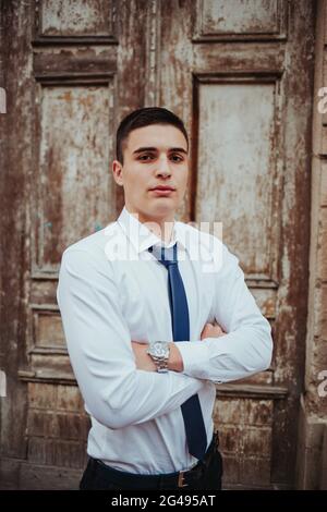 Caucasian young businessman in a tie posing against the door Stock Photo