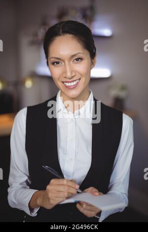 Smiling waitress writing order on notepad Stock Photo