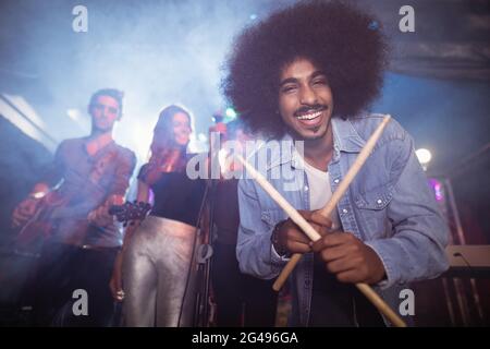 Portrait of drummer holding drum sticks at nightclub Stock Photo