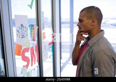 Male executive reading sticky notes on glass door Stock Photo