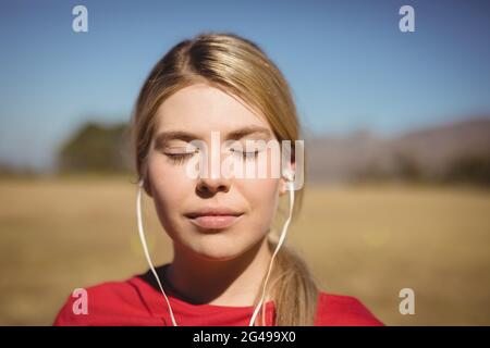 Fit woman listening music on headphones during obstacle course Stock Photo