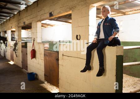 Girl sitting in stable Stock Photo