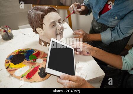 Woman using digital tablet while painting a sculptor Stock Photo