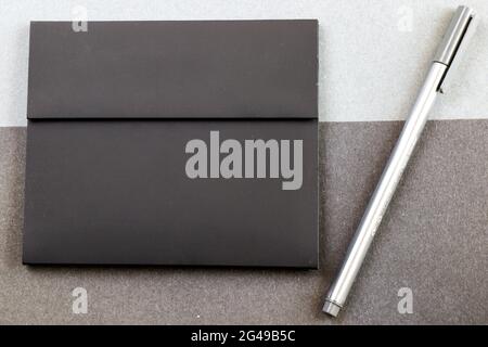 A gray pen next to a black letter envelope on the black and gray papers background Stock Photo
