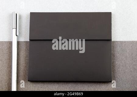 A gray pen next to a black letter envelope on the black and gray papers background Stock Photo