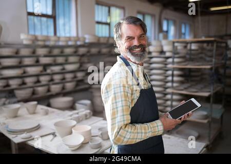 Portrait of male potter using digital tablet Stock Photo