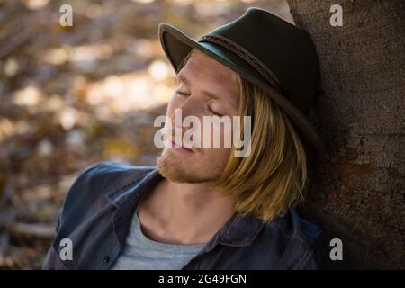Man resting against a tree in the park Stock Photo