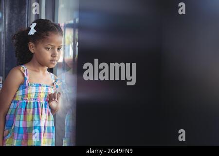 Thoughtful girl looking through window Stock Photo
