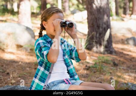 Girl looking through binoculars in the forest Stock Photo