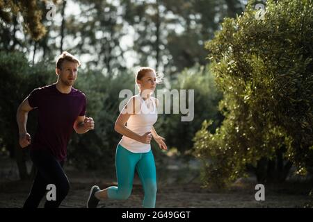 Determined young couple running on field at farm Stock Photo