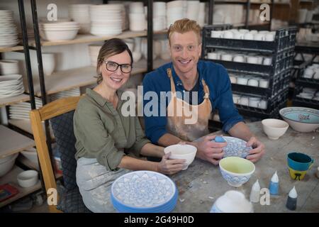 Male and female potter decorating bowl in pottery workshop Stock Photo ...