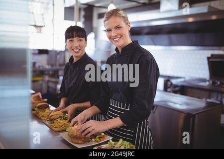 Portrait of smiling female chefs preparing food in kitchen Stock Photo