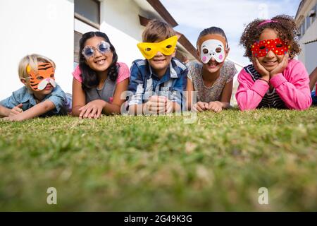 Portrait of children wearing masks lying on field Stock Photo