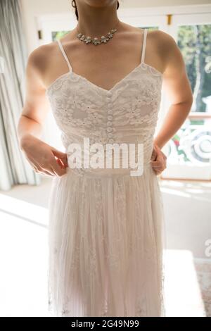 Midsection of woman in wedding dress standing at home Stock Photo