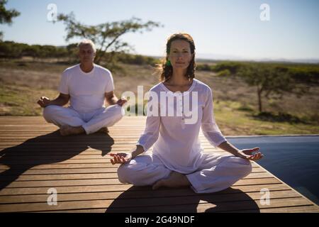 Portrait of couple practicing yoga on wooden plank Stock Photo