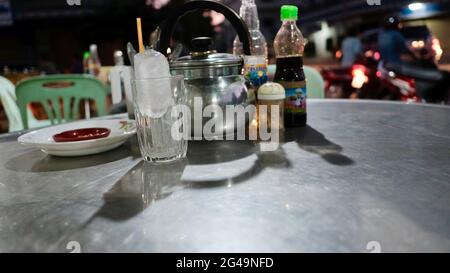 Tea Pot with glass of ice with table place setting at restaurant in Battambang Cambodia Stock Photo