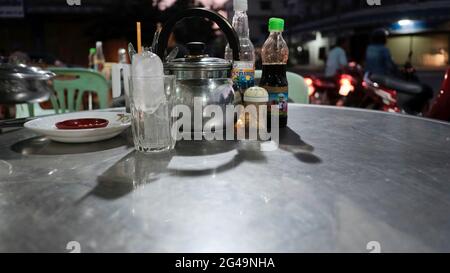 Tea Pot with glass of ice with table place setting at restaurant in Battambang Cambodia Stock Photo