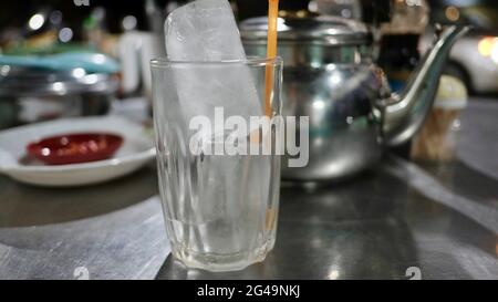 Tea Pot with glass of ice with table place setting at restaurant in Battambang Cambodia Stock Photo