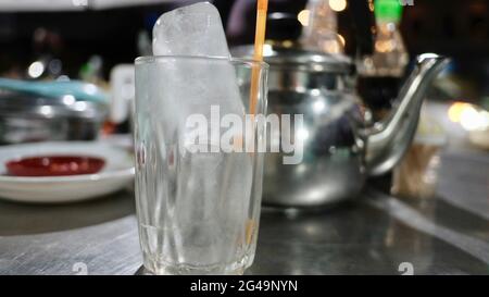 Tea Pot with glass of ice with table place setting at restaurant in Battambang Cambodia Stock Photo