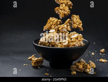 Peanut kozinaki falling in bowl on black background Stock Photo