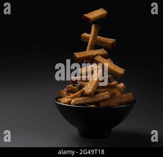 Falling rye bread croutons on black background Stock Photo