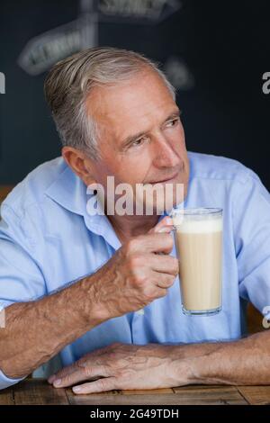 Senior thoughtful man looking away while holding cold coffee Stock Photo
