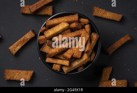 Rye bread croutons on black background, top view Stock Photo
