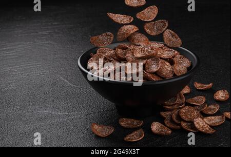 Falling chocolate corn flakes on black background Stock Photo